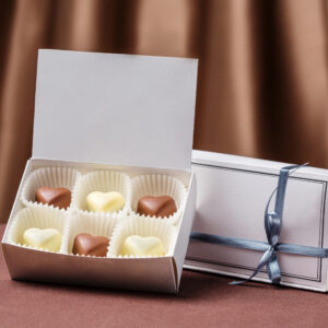 White box with six heart-shaped hand-made chocolate sweets made from milk and white chocolate